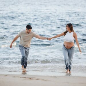pregnant couple on florida beach at water's edge